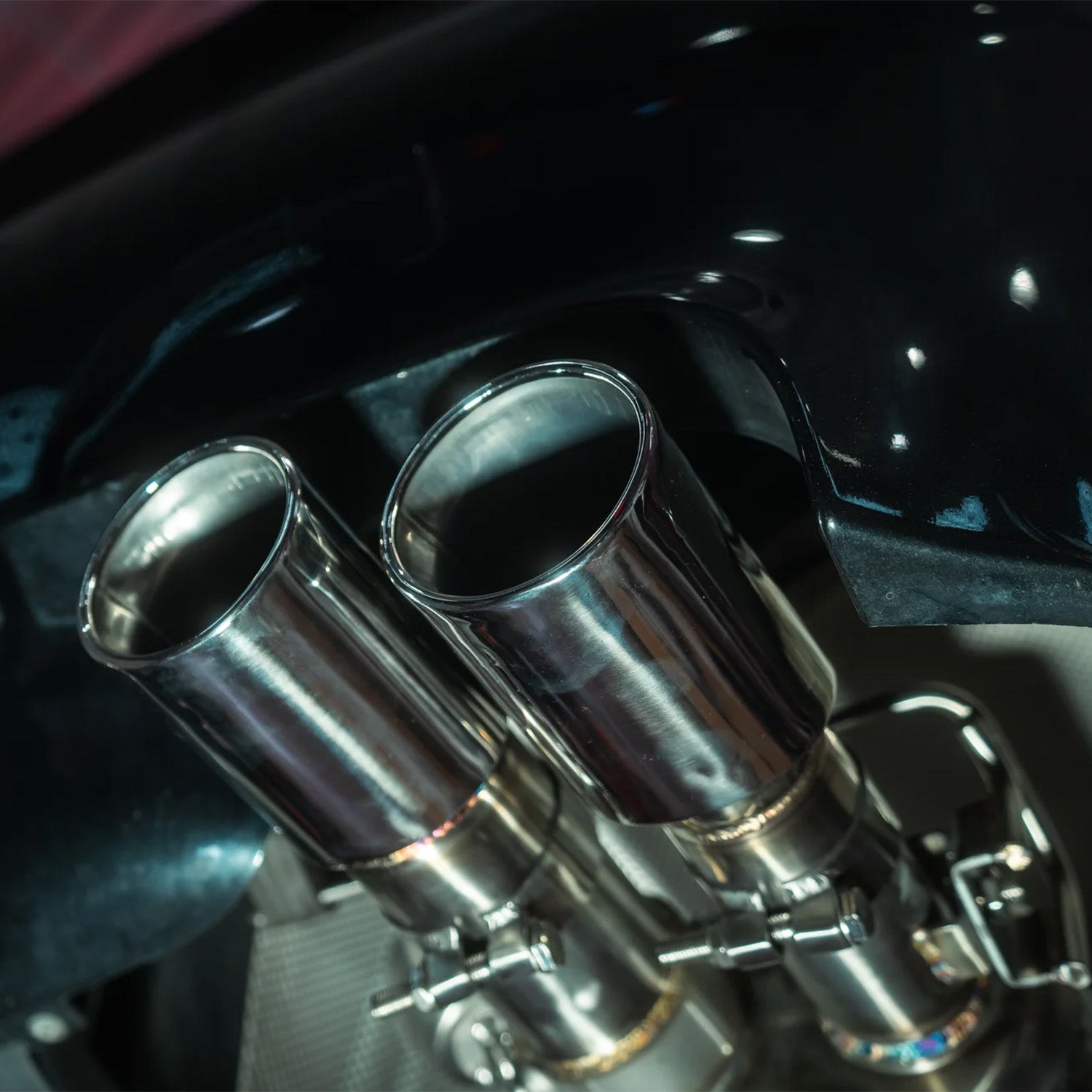 Close-up of a BMW E60 M5 Valvetronic exhaust's dual exhaust pipes with a dark background